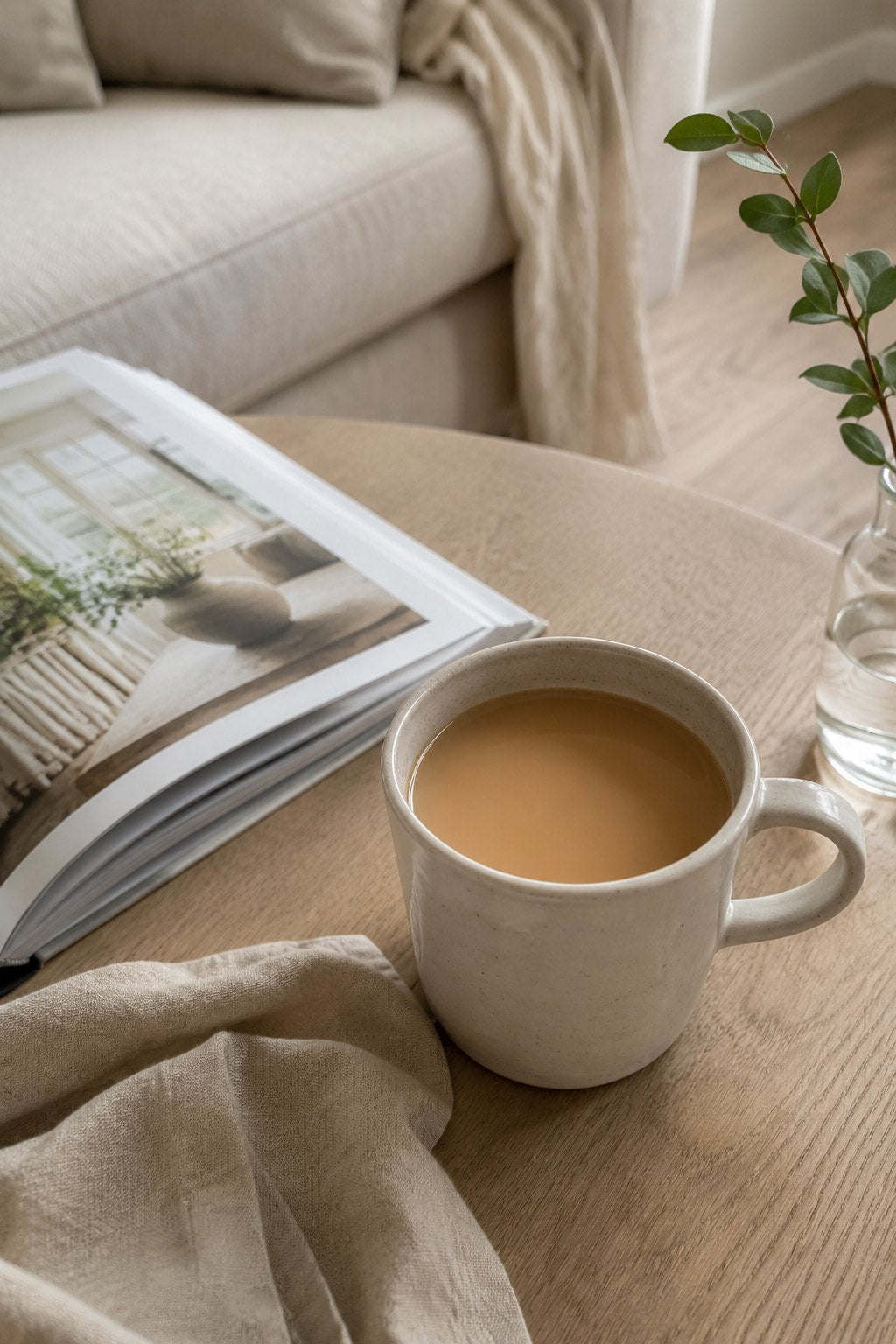A mug of tea beside an open magazine on a pale wooden table
